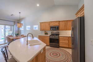 Kitchen featuring pendant lighting, a kitchen island with sink, sink, light tile patterned floors, and appliances with stainless steel finishes