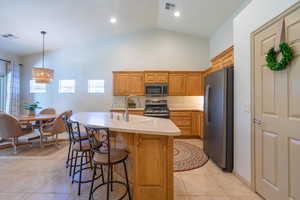 Kitchen featuring a kitchen island with sink, hanging light fixtures, sink, light tile  flooring, and matt finish, smudge-proof, stainless steel appliances