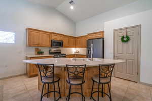 Kitchen featuring sink, stainless steel appliances, a kitchen island with sink, and light tile patterned flooring