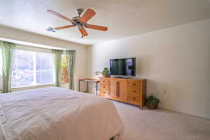 Primary bedroom featuring light carpet and ceiling fan