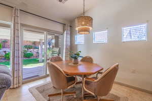 Tiled dining room with sliding glass doors, lofted ceiling, and a healthy amount of sunlight