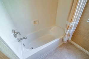 Bathroom featuring tile patterned flooring and shower / bathtub combination with curtain