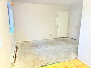 Empty room with light wood-type flooring and a baseboard heating unit