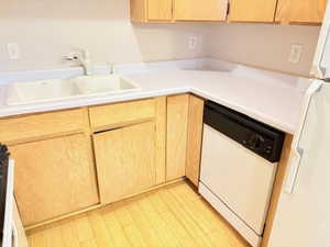 Kitchen with dishwasher, sink, refrigerator, light brown cabinetry, and light wood-type flooring