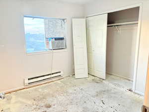 Unfurnished bedroom with a closet, cooling unit, and a baseboard heating unit