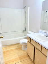 Full bathroom with wood-type flooring, vanity, toilet, and tub / shower combination