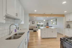 Kitchen with white cabinets, tasteful backsplash, sink, and light hardwood / wood-style flooring