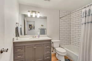 Full bathroom with shower / bath combo with shower curtain, vanity, wood-type flooring, and toilet