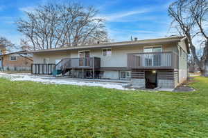 Back of property with a yard and a wooden deck