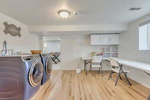 Laundry room featuring cabinets, light hardwood / wood-style flooring, and washing machine and clothes dryer