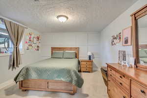 Bedroom with light carpet and a textured ceiling