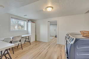 Office space featuring washing machine and dryer, a textured ceiling, and light wood-type flooring