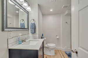 Bathroom with wood-type flooring, vanity, a textured ceiling, and toilet