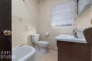 Bathroom featuring tile patterned flooring, vanity, toilet, and a tub