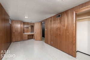 Unfurnished bedroom featuring wood walls, a closet, and built in desk