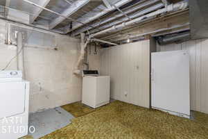 Basement with washing machine and clothes dryer and white refrigerator