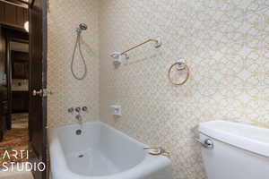 Bathroom featuring tile walls and toilet