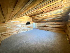 Bonus room with wooden ceiling, vaulted ceiling, and wooden walls