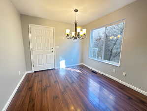 Dining area with a chandelier, dark wood-type flooring, and a textured ceiling