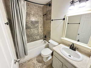 Full bathroom with toilet, vanity, and shower / tub combo with curtain