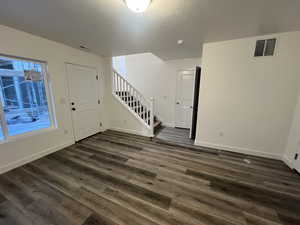 Foyer entrance with a textured ceiling and dark hardwood / wood-style floors