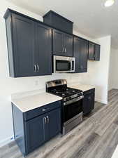 Kitchen featuring appliances with stainless steel finishes, a textured ceiling, and light hardwood / wood-style floors