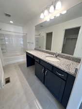 Bathroom with vanity, tile patterned floors, and tiled shower / bath combo