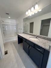 Bathroom featuring tile patterned floors, vanity, and tiled shower / bath