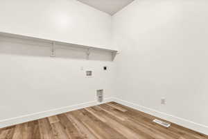 Clothes washing area with hardwood / wood-style floors, hookup for an electric dryer, and washer hookup