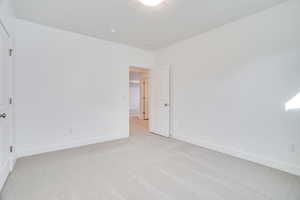 Unfurnished bedroom featuring light carpet and baseboards