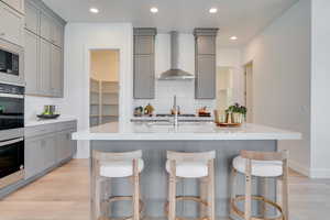 Kitchen featuring gray cabinetry, light wood-style flooring, tasteful backsplash, stainless steel appliances, and recessed lighting