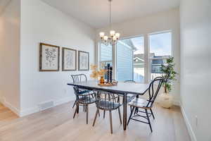 Dining area with light wood-style flooring and a chandelier