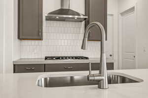 Kitchen with wall chimney exhaust hood, sink, and backsplash