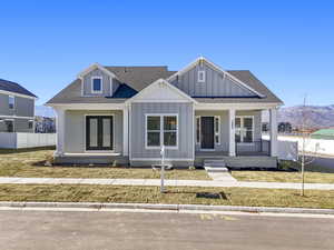 View of front facade featuring roof with shingles, a porch, board and batten siding, and a mountain view