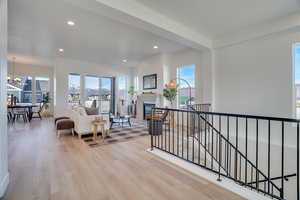 Living area with recessed lighting, light wood-type flooring, a glass covered fireplace, and a chandelier