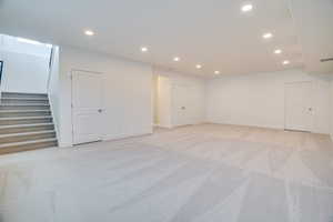 Below grade area with light colored carpet, recessed lighting, and stairs