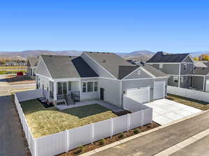 View of front facade with a fenced front yard, roof with shingles, a mountain view, concrete driveway, and an attached garage