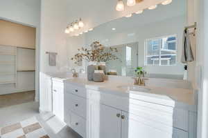 Bathroom with double vanity, a shower stall, a spacious closet, and light tile patterned floors