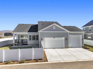 View of front of home featuring a fenced front yard, a shingled roof, board and batten siding, and concrete driveway