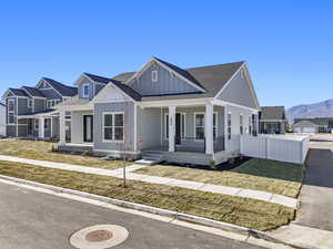 Modern farmhouse style home with roof with shingles, a porch, board and batten siding, and a mountain view