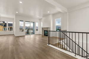 Unfurnished living room featuring hardwood / wood-style flooring, a notable chandelier, and a healthy amount of sunlight