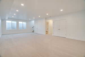 Unfurnished room featuring recessed lighting, light carpet, and stairway
