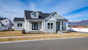 Modern farmhouse style home featuring covered porch, board and batten siding, a shingled roof, and a mountain view