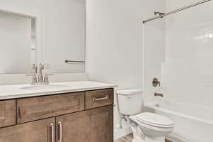 Full bathroom with hardwood / wood-style flooring, vanity, toilet, and shower / bathing tub combination