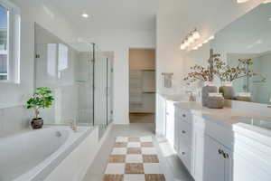 Bathroom with a spacious closet, a bath, double vanity, a shower stall, and light tile patterned floors