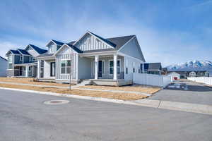 Modern farmhouse style home with a porch, a mountain view, roof with shingles, and board and batten siding