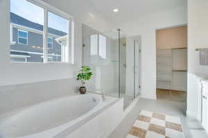 Full bath featuring a walk in closet, a bath, a stall shower, light tile patterned flooring, and recessed lighting