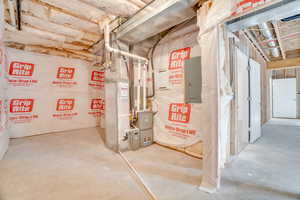 Utility room featuring electric panel and heating unit