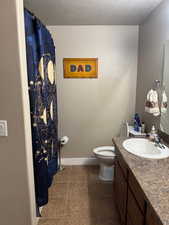 Bathroom featuring tile patterned floors, vanity, a textured ceiling, and toilet