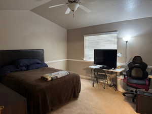 Bedroom with ceiling fan, light carpet, and vaulted ceiling